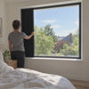 Closing a Noctis Blinds panel left to right in a sunlit bedroom until the room is in complete blackout
